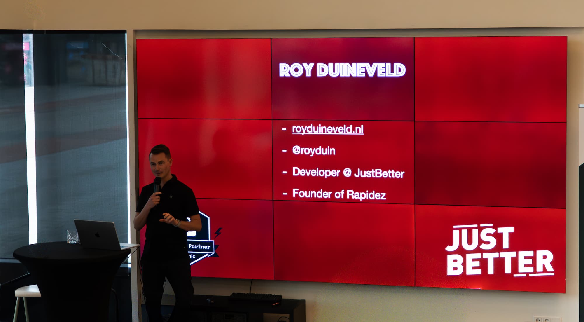Roy from JustBetter standing next to his laptop and in front of a big screen giving a presentation about the Runway addon